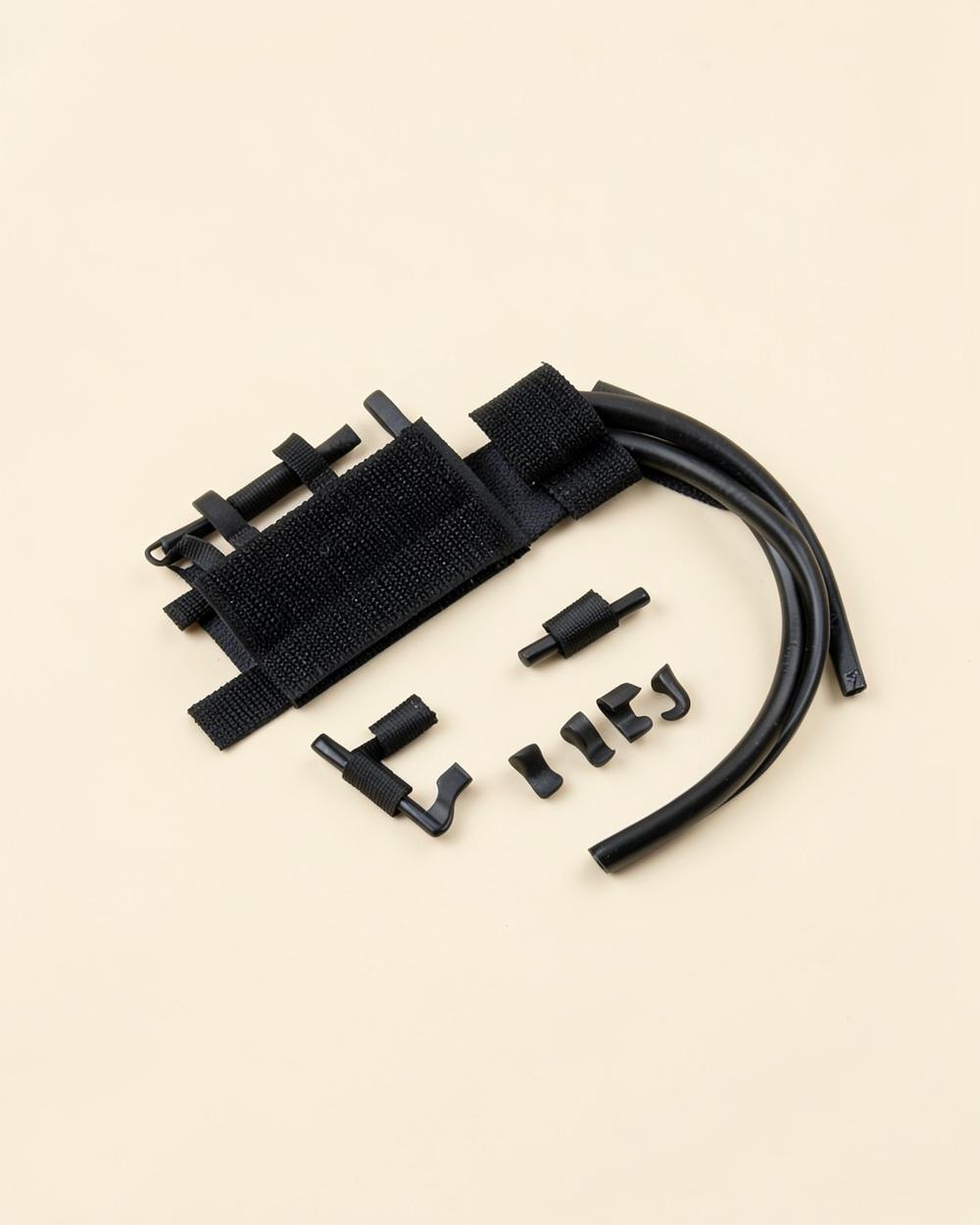 Kit de gestion des câbles noir : attaches, clips et gaine sur un fond beige clair