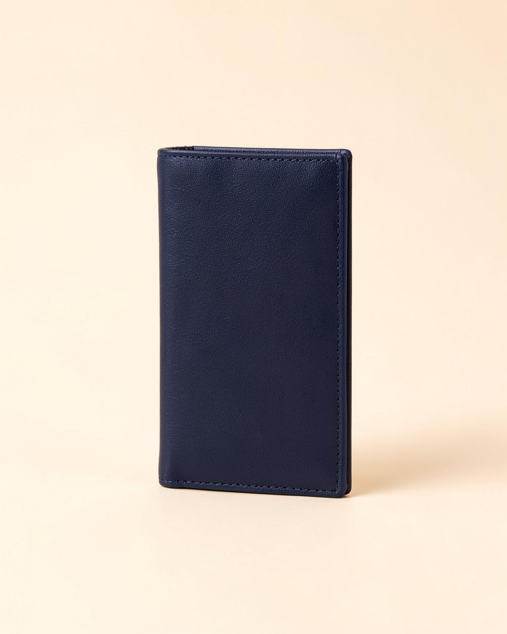 Porte-cartes fin bleu navy debout sur un fond beige clair
