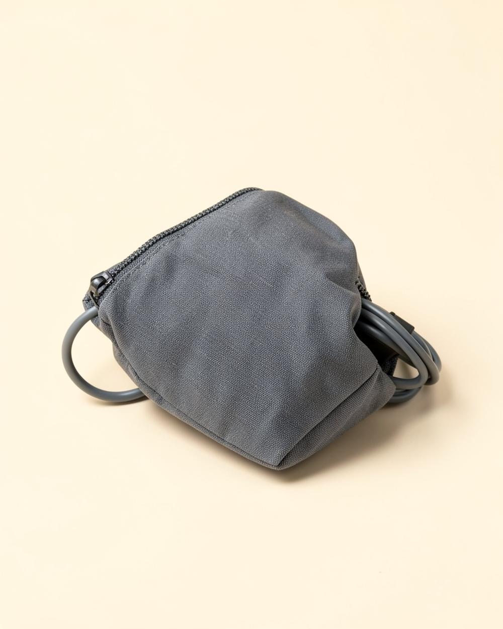 Pochette de rangement graphite avec un câble, sur un fond beige clair